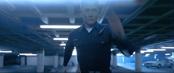 Movie still from “Terminator 2: Judgment Day” (1991), directed by James Cameron – A man standing in a parking garage holding a gun; Medium shot, Low angle