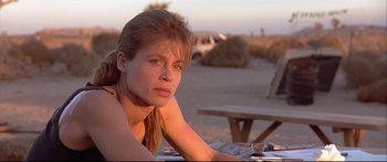 Movie still from “Terminator 2: Judgment Day” (1991), directed by James Cameron – A woman sitting at a picnic table in the desert; Close Up shot, Low angle