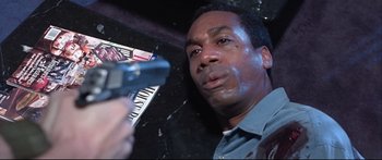 Movie still from “Terminator 2: Judgment Day” (1991), directed by James Cameron – A man holding a gun in front of a wall; Close Up shot, High angle