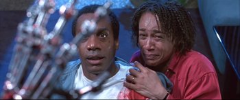 Movie still from “Terminator 2: Judgment Day” (1991), directed by James Cameron – A man and a woman standing next to each other in front of a chain link fence; Close Up shot, Low angle