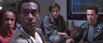 Movie still from “Terminator 2: Judgment Day” (1991), directed by James Cameron – A group of people sitting in a living room together; Close Up shot, Low angle
