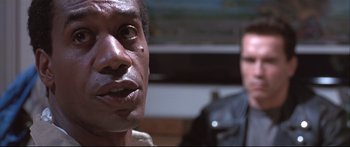 Movie still from “Terminator 2: Judgment Day” (1991), directed by James Cameron – A man's face with a man in the background; Close Up shot, Low angle