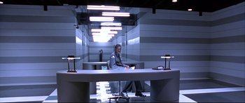 Movie still from “Terminator 2: Judgment Day” (1991), directed by James Cameron – A man sitting at a table in a room; Wide shot, Low angle