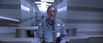 Movie still from “Terminator 2: Judgment Day” (1991), directed by James Cameron – A man in a police uniform sitting in a room; Medium shot, Low angle