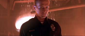 Movie still from “Terminator 2: Judgment Day” (1991), directed by James Cameron – A man in a police uniform standing in front of a wall; Close Up shot, Low angle