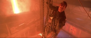 Movie still from “Terminator 2: Judgment Day” (1991), directed by James Cameron – A man standing next to a bunch of chains in a room; Medium shot, Low angle