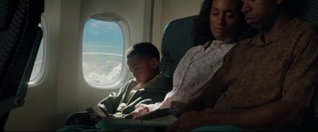 Movie still from “Terminator Genisys” (2015), directed by Alan Taylor – A woman and a child sitting on a plane looking at an ipad; Medium shot, High angle