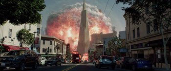 Movie still from “Terminator Genisys” (2015), directed by Alan Taylor – A city street with cars and a red double - decker bus in front of a tall building; Extreme Wide shot, Low angle