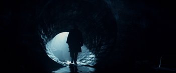 Movie still from “Terminator Genisys” (2015), directed by Alan Taylor – A person is walking through a tunnel in the dark; Wide shot, Low angle