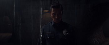 Movie still from “Terminator Genisys” (2015), directed by Alan Taylor – A man in a police uniform standing in a dark room; Medium shot, Low angle