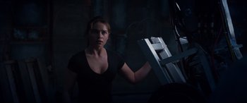 Movie still from “Terminator Genisys” (2015), directed by Alan Taylor – A woman standing in a dark room with a ladder; Medium shot, Over the shoulder angle