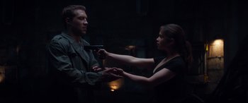 Movie still from “Terminator Genisys” (2015), directed by Alan Taylor – A man and a woman holding guns in a dark room; Medium shot, Over the shoulder angle