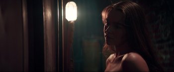 Movie still from “Terminator Genisys” (2015), directed by Alan Taylor – A woman standing in front of a mirror in a dimly - lit room; Close Up shot, Over the shoulder angle