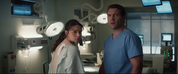 Movie still from “Terminator Genisys” (2015), directed by Alan Taylor – A man and a woman standing next to each other in an operating room; Medium shot, Over the shoulder angle
