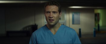 Movie still from “Terminator Genisys” (2015), directed by Alan Taylor – A man in a blue shirt is standing in a room; Close Up shot, Over the shoulder angle