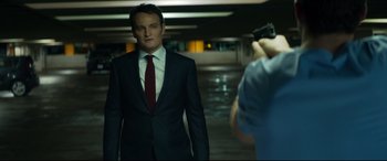 Movie still from “Terminator Genisys” (2015), directed by Alan Taylor – A man wearing a suit and tie holding a gun; Medium shot, Over the shoulder angle