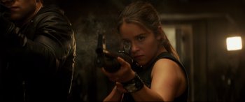 Movie still from “Terminator Genisys” (2015), directed by Alan Taylor – A woman is holding a gun in her hand; Close Up shot, Over the shoulder angle