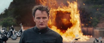 Movie still from “Terminator Genisys” (2015), directed by Alan Taylor – A man standing in front of a burning building; Close Up shot, Over the shoulder angle