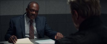 Movie still from “Terminator Genisys” (2015), directed by Alan Taylor – A man in a suit and tie sitting at a table with another man; Close Up shot, Over the shoulder angle