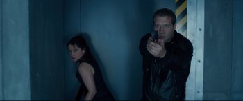 Movie still from “Terminator Genisys” (2015), directed by Alan Taylor – A man and a woman holding a gun in a room; Medium shot, Low angle
