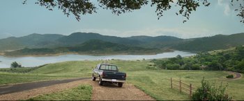Movie still from “Terminator Genisys” (2015), directed by Alan Taylor – A truck parked on the side of a road near a body of water; Extreme Wide shot, High angle
