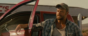 Movie still from “Texas Chainsaw Massacre” (2022), directed by David Blue Garcia – A man sitting in the driver's seat of a red truck; Close Up shot, Over the shoulder angle