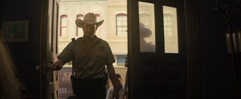 Movie still from “Texas Chainsaw Massacre” (2022), directed by David Blue Garcia – A man in a cowboy hat standing in front of a door; Medium shot, Low angle