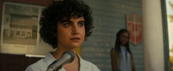 Movie still from “Texas Chainsaw Massacre” (2022), directed by David Blue Garcia – A person with a microphone in front of a brick wall; Close Up shot, Over the shoulder angle