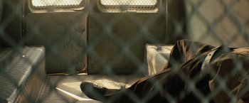 Movie still from “Texas Chainsaw Massacre” (2022), directed by David Blue Garcia – A person sitting on a bench in a jail cell; Medium shot, Low angle