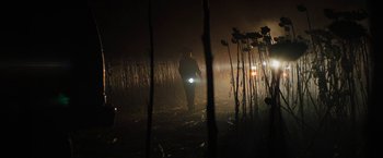 Movie still from “Texas Chainsaw Massacre” (2022), directed by David Blue Garcia – A man is walking through a field at night with a flashlight; Wide shot, Low angle