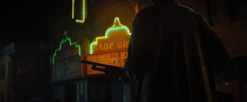 Movie still from “Texas Chainsaw Massacre” (2022), directed by David Blue Garcia – A man holding a rifle in front of a neon sign; Wide shot, Low angle