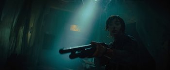 Movie still from “Texas Chainsaw Massacre” (2022), directed by David Blue Garcia – A man holding a gun in a dark room; Medium shot, Low angle