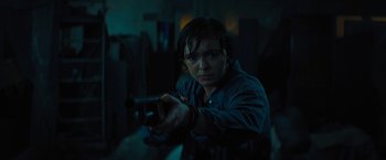 Movie still from “Texas Chainsaw Massacre” (2022), directed by David Blue Garcia – A person holding a gun in a dark room; Medium shot, Low angle