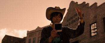 Movie still from “Texas Chainsaw Massacre” (2022), directed by David Blue Garcia – A man in a cowboy hat looking at a cell phone; Close Up shot, Low angle