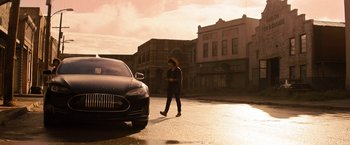 Movie still from “Texas Chainsaw Massacre” (2022), directed by David Blue Garcia – A person walking on the sidewalk near a car; Wide shot, Low angle