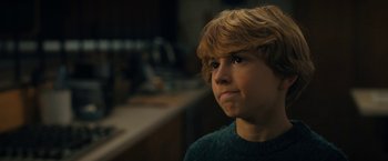 Movie still from “The Adam Project” (2022), directed by Shawn Levy – A young boy with blonde hair and a green sweater; Close Up shot, Over the shoulder angle