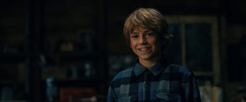 Movie still from “The Adam Project” (2022), directed by Shawn Levy – A young boy smiling for the camera in front of a bookshelf; Close Up shot, Over the shoulder angle