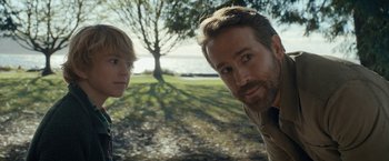 Movie still from “The Adam Project” (2022), directed by Shawn Levy – A man and a boy standing next to each other in front of a tree; Close Up shot, Over the shoulder angle