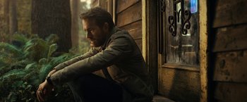 Movie still from “The Adam Project” (2022), directed by Shawn Levy – A man sitting on the porch of a wooden house; Medium shot, Over the shoulder angle