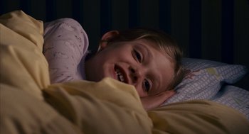 Movie still from “Babel” (2006), directed by Alejandro G. Iñárritu – A little girl laying in a bed smiling at the camera; Close Up shot, High angle