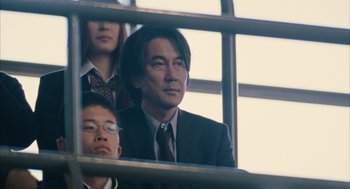 Movie still from “Babel” (2006), directed by Alejandro G. Iñárritu – A man wearing a suit and tie sitting next to another man; Close Up shot, Low angle