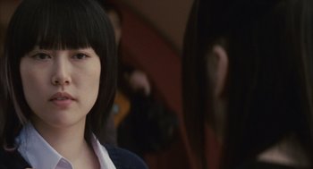 Movie still from “Babel” (2006), directed by Alejandro G. Iñárritu – A young woman with bangs is looking at the camera; Close Up shot, Over the shoulder angle