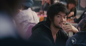 Movie still from “Babel” (2006), directed by Alejandro G. Iñárritu – A man sitting in front of a group of people; Close Up shot, Over the shoulder angle