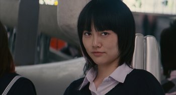 Movie still from “Babel” (2006), directed by Alejandro G. Iñárritu – A woman with black hair wearing a white shirt and a black sweater; Close Up shot, Low angle