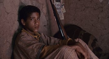 Movie still from “Babel” (2006), directed by Alejandro G. Iñárritu – A young man holding a rifle in a room; Close Up shot, High angle