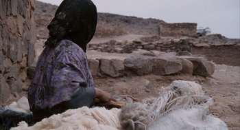 Movie still from “Babel” (2006), directed by Alejandro G. Iñárritu – A woman sitting on the side of the road near a pile of wool; Medium shot, Over the shoulder angle