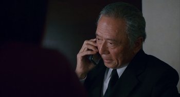 Movie still from “Babel” (2006), directed by Alejandro G. Iñárritu – An older man wearing a suit and tie talking on a cell phone; Close Up shot, High angle