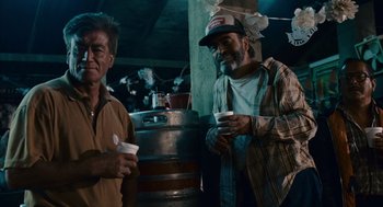 Movie still from “Babel” (2006), directed by Alejandro G. Iñárritu – Two men standing next to each other in front of a beer barrel; Medium shot, Low angle