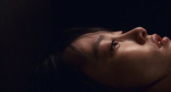 Movie still from “Babel” (2006), directed by Alejandro G. Iñárritu – A person's face with a dark background; Extreme Close Up shot, Overhead angle