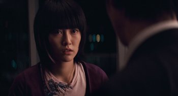 A young asian woman looking at a man in a dark room